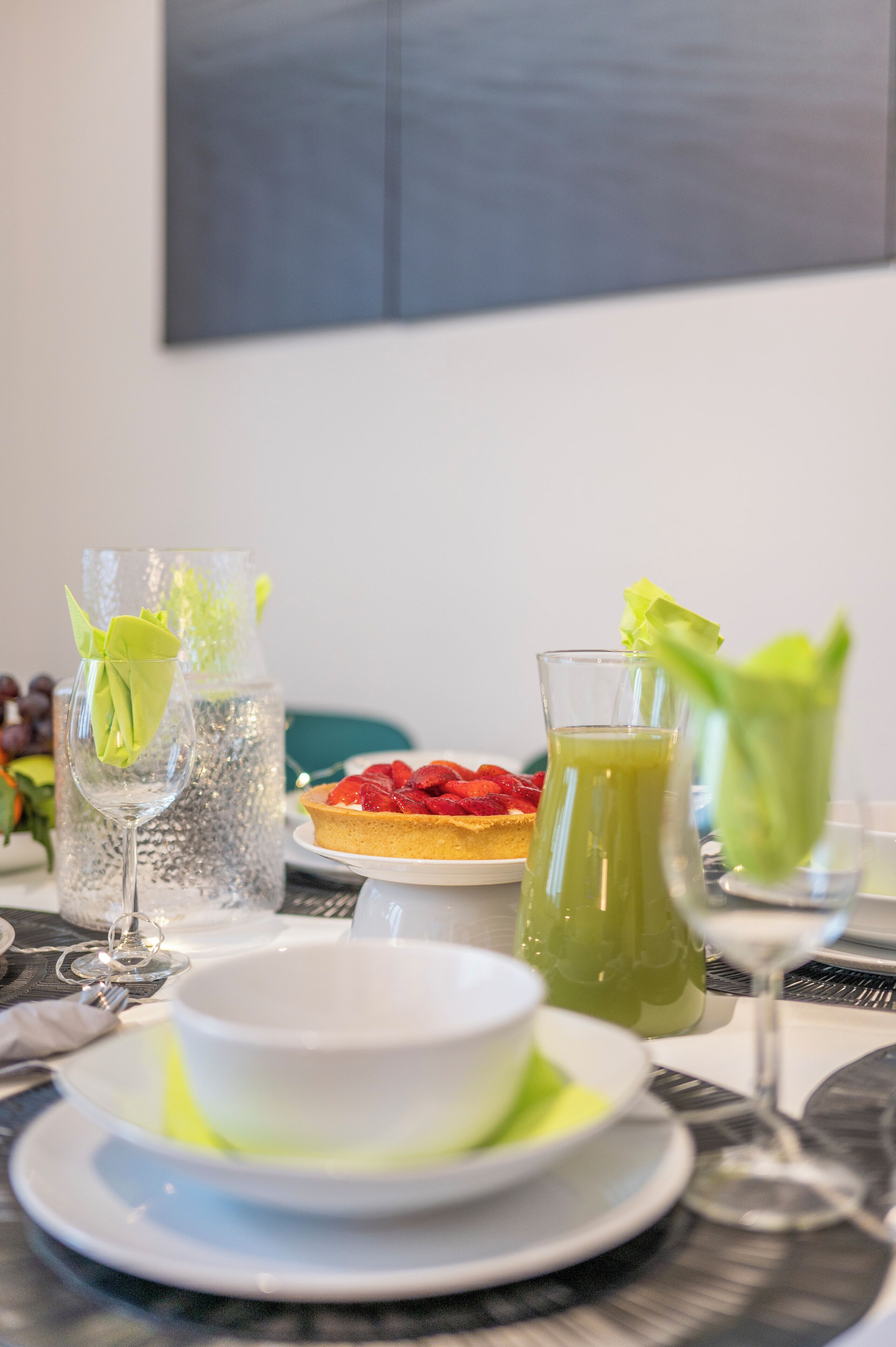 A dining table with a plate of food, a pitcher of green drink, and a glass of water.