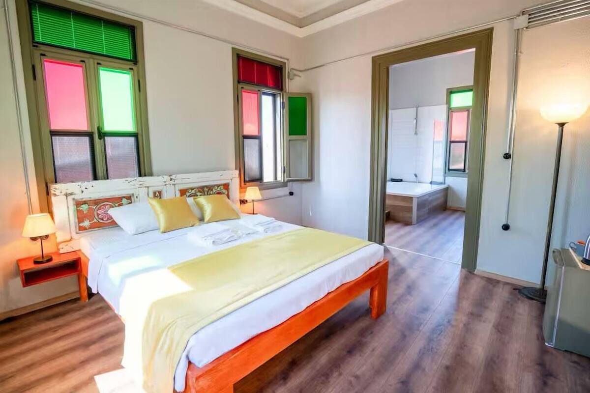 Ein Schlafzimmer mit einem Bett, Nachttischen, einem Spiegel und einer Tür zu einem Badezimmer.