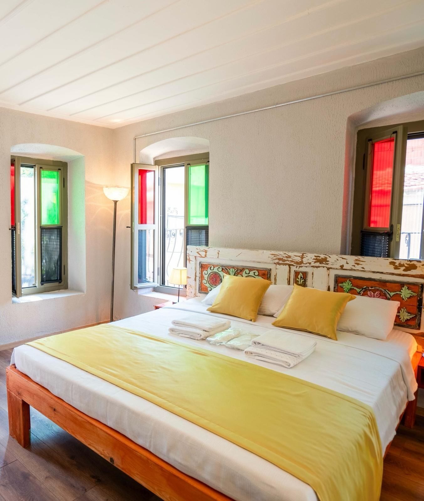 A bedroom with a bed, a nightstand, a lamp, and a window with blinds.