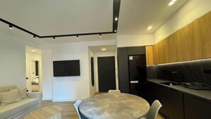 Un salon moderne avec une table à manger ronde, un canapé et un téléviseur fixé au mur.