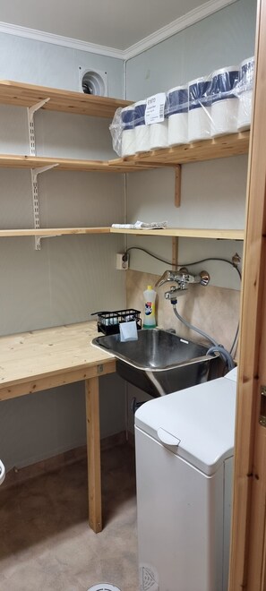 A compact kitchen with a sink, a small refrigerator, and shelves with packaged goods. - Tranquil apartment with WiFi in charming Trøndelag (Trøndelag)