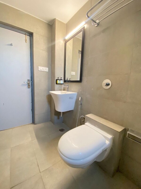 Un baño moderno con inodoro, lavamanos y espejo.