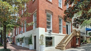 A brick building with a white facade, large windows, and a staircase leading to the entrance. - Suite Liberty, Elegant | Refined | Chippewa Square (Savannah)