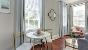 A dining area with a round table, chairs, and a vase. - Suite Liberty, Elegant | Refined | Chippewa Square (Savannah)