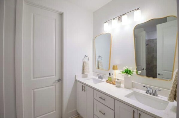 A bathroom with a white door, a vanity with a mirror, and a sink.