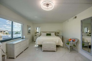 Un dormitorio con una cama grande, una ventana, un radiador, una silla y un espejo.