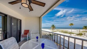 A balcony with a table, chairs, and a ceiling fan.