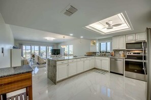 Una cocina moderna con armarios blancos, encimera de granito y electrodomésticos de acero inoxidable.