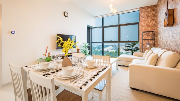 A modern living room with a dining area, large windows, a flat-screen TV, and a guitar on the wall.