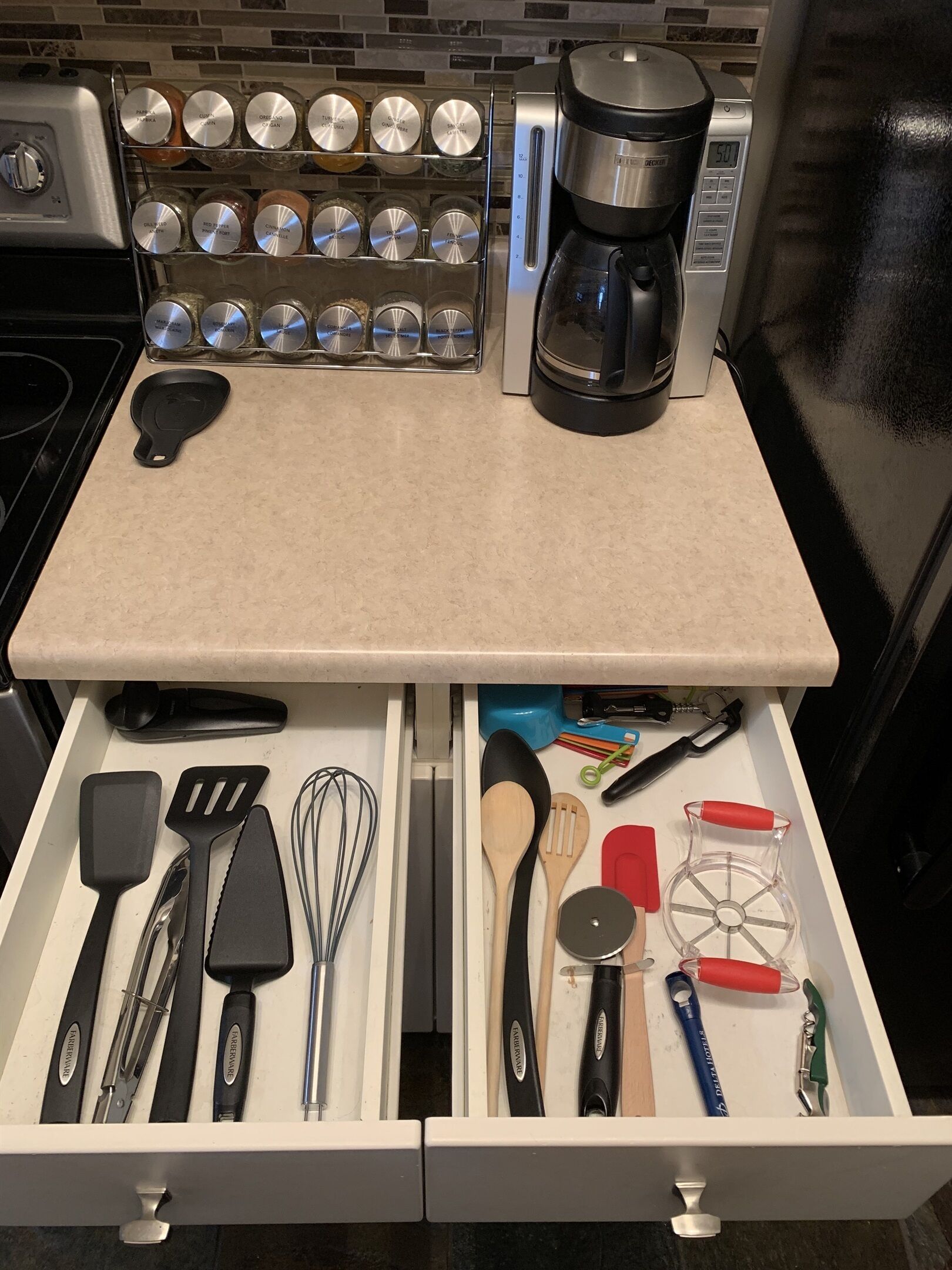 A kitchen counter with a coffee maker and spice jars.