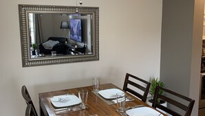 A dining room with a wooden table set for four, a ceiling fan, and a mirror on the wall. - Cozy Condo close to LRT, Stadium and Expo Center. (EDMONTON)