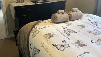 Een slaapkamer met een bed, een dressoir, een televisie en een decoratie aan de muur.