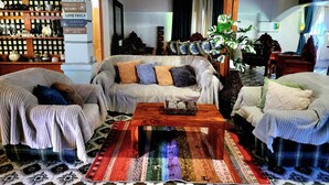 A cozy living room with a sofa set, a coffee table, and a decorative rug. There are wall-mounted shelves with various items and a sign with inspirational quotes. - 3 Bed House - Sleeps 20 - Pets - Pool - Garden (Aringay)