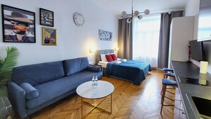 Ein modernes Hotelzimmer mit einer Couch, einem Bett, einem kleinen Tisch und einem Fernseher.