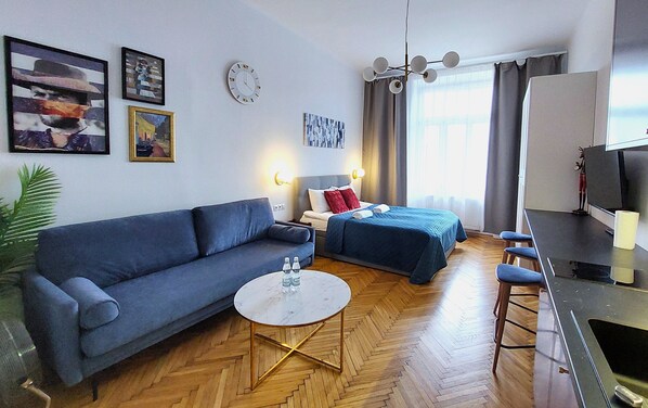 Ein modernes Hotelzimmer mit einer Couch, einem Bett, einem kleinen Tisch und einem Fernseher.
