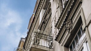 Ein Gebäude mit aufwendigen architektonischen Details, darunter dekorative Verzierungen und ein Balkon mit Metallgeländern.