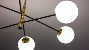 Eine Decke mit einem modernen Kronleuchter mit mehreren kugelförmigen Leuchten.