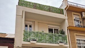 A two-story building with a balcony, a gated entrance, and a parked scooter.