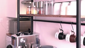 A kitchen with a coffee machine, a toaster, and shelves with jars of pasta and spices. - Hyper-centre de Perpignan : Studio chic à deux pas de tout ! (Perpignan)