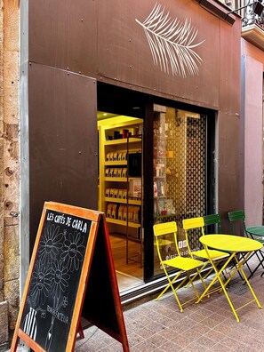 An outdoor seating area with yellow tables and chairs in front of a café with a chalkboard sign. - Hyper-centre de Perpignan : Studio chic à deux pas de tout ! (Perpignan)