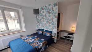 A bedroom with a bed, a desk, and a chair.