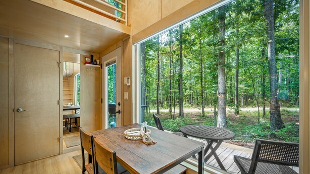 A modern wooden interior with a large window overlooking a forest. - Boho Bungalow-unique & cozy tiny home (Mentone)
