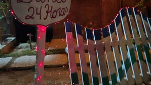 A wooden hut with a heart-shaped sign reading "Banco 24 Horas".