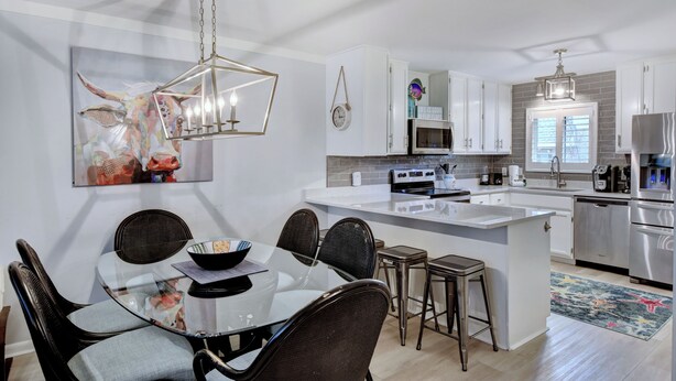 A modern kitchen with white cabinets, a central island, and stainless steel appliances. - Great condo just a short walk to the beach (St. Simons Island)
