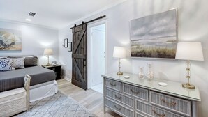 A bedroom with a bed, bedside tables, a dresser, and a painting on the wall. - Great condo just a short walk to the beach (St. Simons Island)