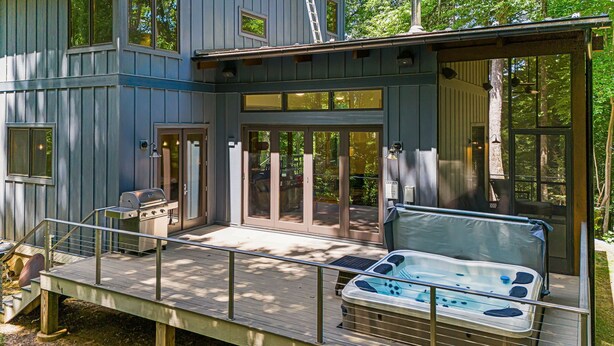 A modern cabin with a deck, a hot tub, and a grill. - Secluded 3BR home on 30 acres near Green River Gorge with hot tub & trails (Saluda)