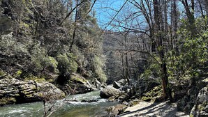 A river flowing through a forested area with rocky terrain and sandy banks. - Secluded 3BR home on 30 acres near Green River Gorge with hot tub & trails (Saluda)