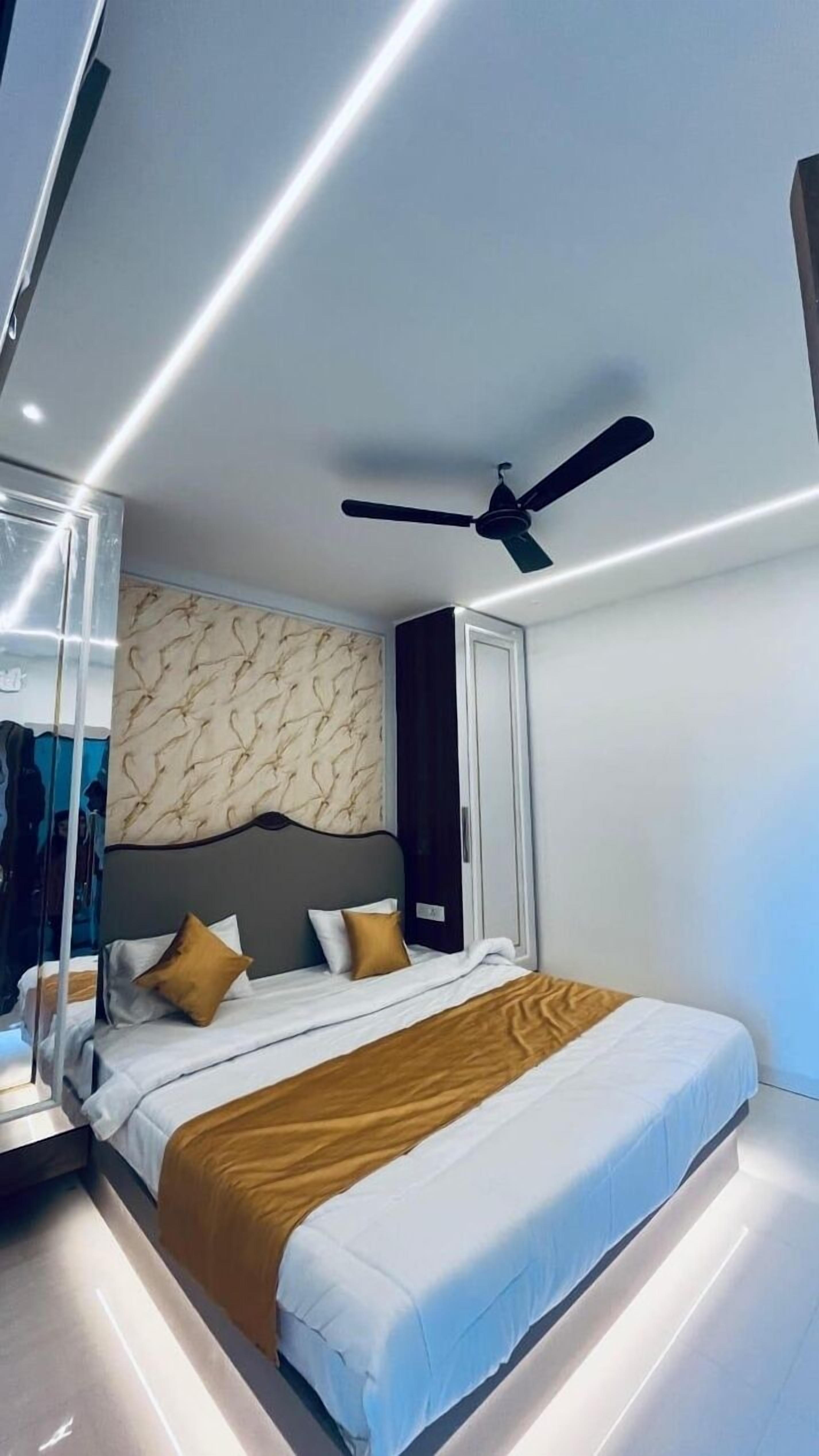 Une chambre d’hôtel moderne avec un grand lit, un ventilateur de plafond et une armoire.