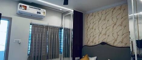 A modern bedroom with a bed, ceiling fan, air conditioning unit, and a patterned wall.