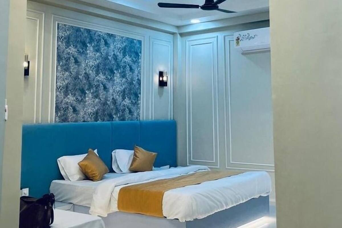 Camera d'albergo moderna con un letto matrimoniale, un letto singolo, una ventola a soffitto e un pannello decorativo.