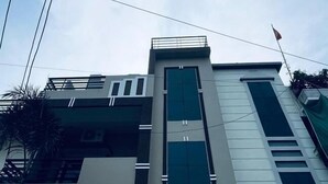 A multi-story building with a modern architectural design, featuring large windows and a prominent entrance with signage. - Hotel Shivngan (Ujjain)