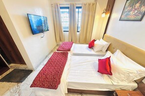 A hotel room with two beds, a TV, and a painting on the wall. - Hotel The Ceremony (Bhiwandi)