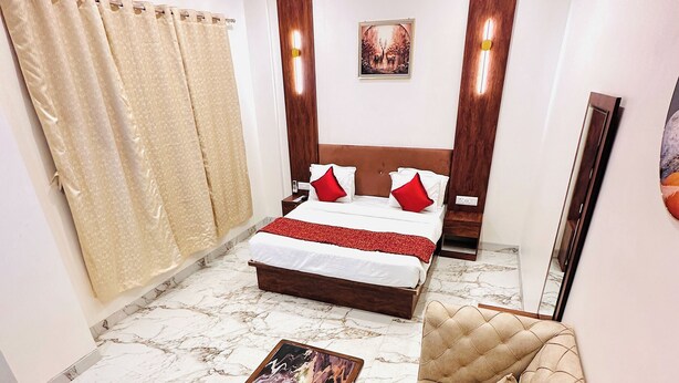 A hotel room with a bed, a sofa, a coffee table, and a ceiling fan. - Hotel The Ceremony (Bhiwandi)