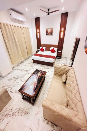 Una habitación de hotel con cama, sofá, mesa de centro y ventilador de techo.
