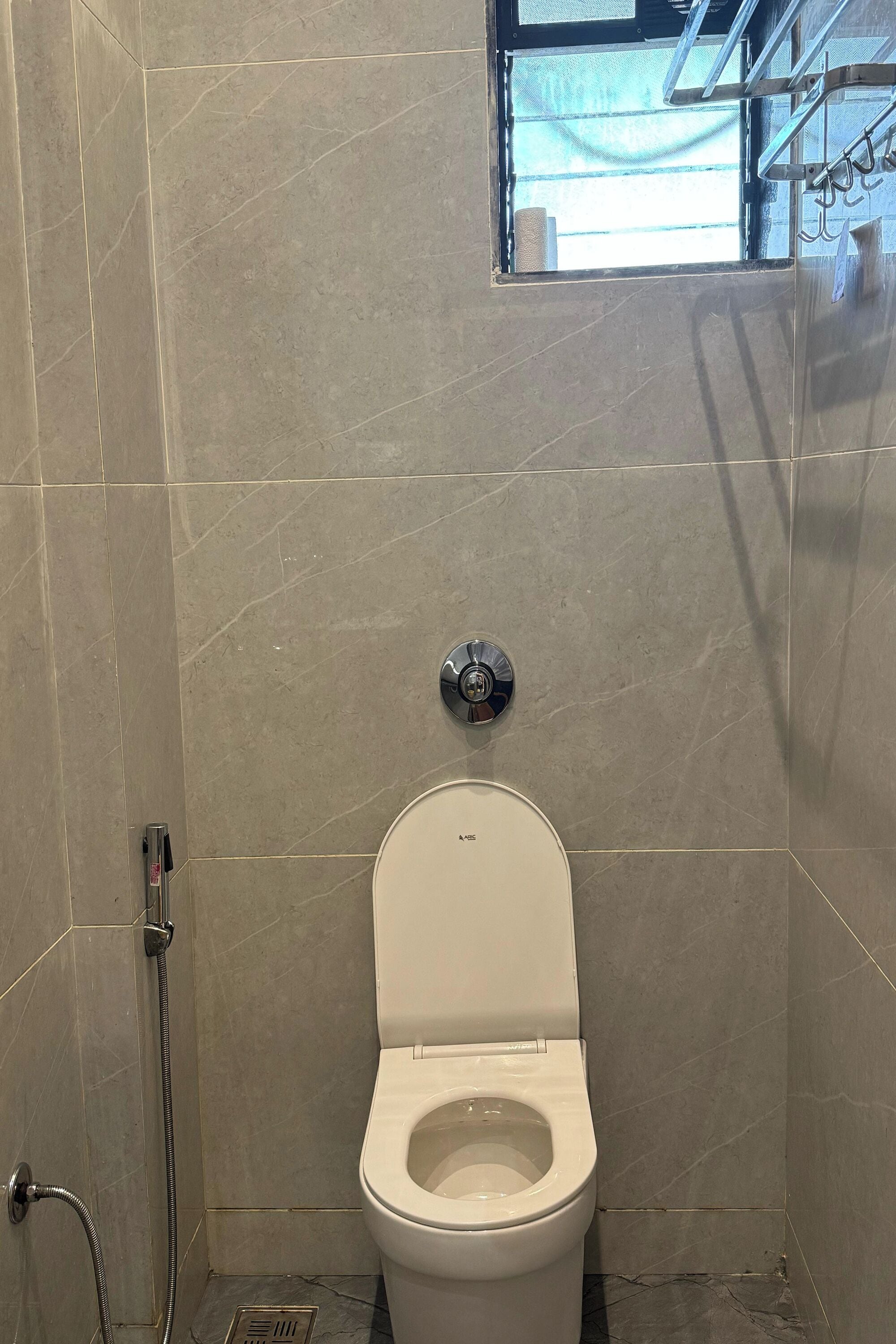 A bathroom with a toilet, a shower, and a window.