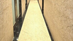 A corridor with marble walls and black-tiled floors, featuring elevators and doors. - Hotel The Ceremony (Bhiwandi)