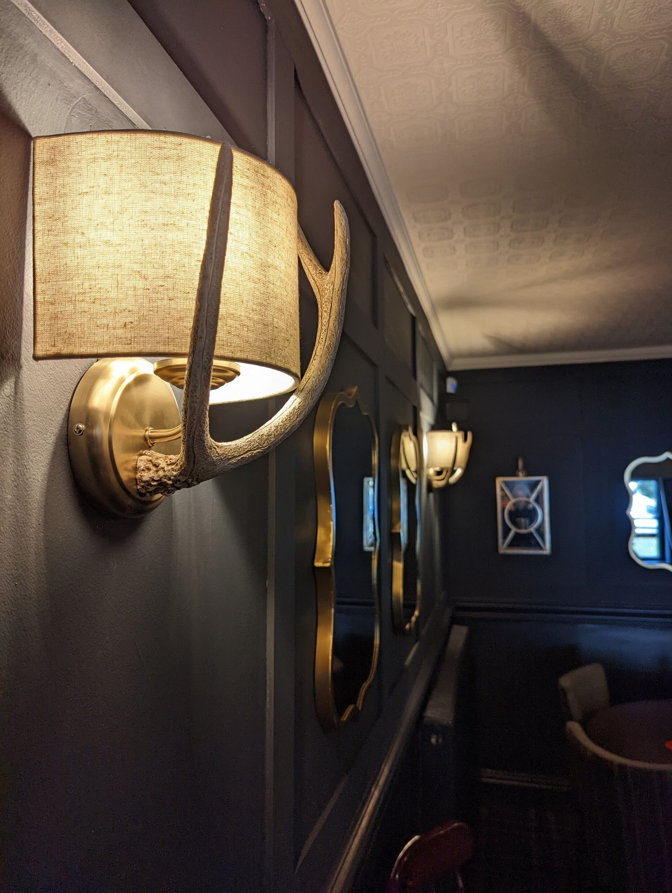 A wall-mounted lamp with a textured shade and a brass base.