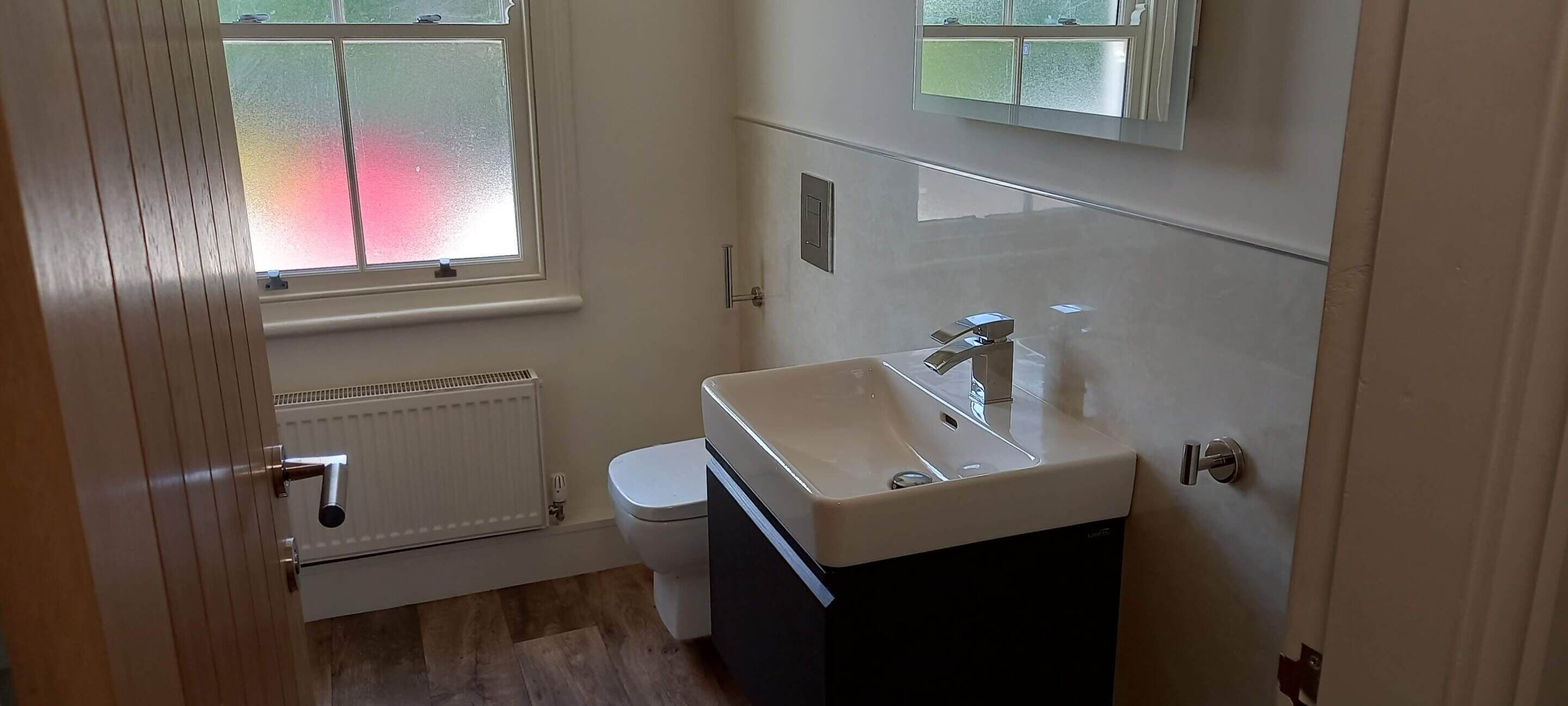 Een kleine badkamer met toilet, wastafel en raam.