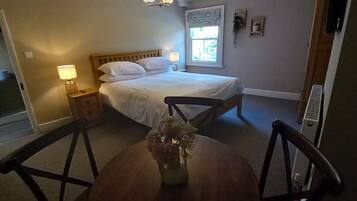 A bedroom with a bed, bedside tables, a window, and a dining table with chairs.