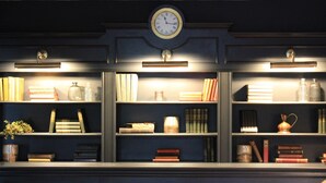A bookshelf with books, decorative items, and a clock. - The Buck Hotel (Middlesbrough)