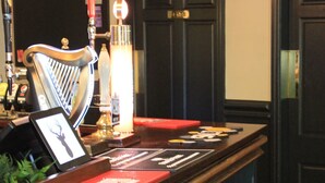 A bar area with a harp, stools, and a counter with various items. - The Buck Hotel (Middlesbrough)