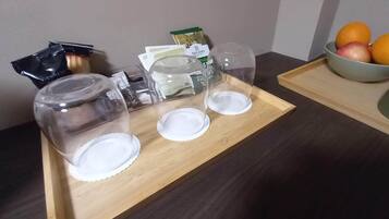 Un plateau en bois sur lequel sont disposés trois bocaux en verre transparent, un récipient transparent et un bol de fruits.