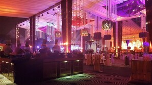 Un área de bar con alfombra estampada, luces colgantes y un escenario al fondo.