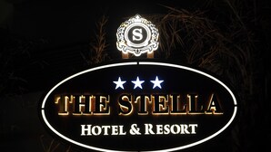 Señal para 'The Stella Hotel & Resort', con un emblema decorativo y tres estrellas sobre el nombre.