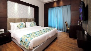 Una habitación de hotel moderna con una cama grande, un televisor de pantalla plana y piso de madera.