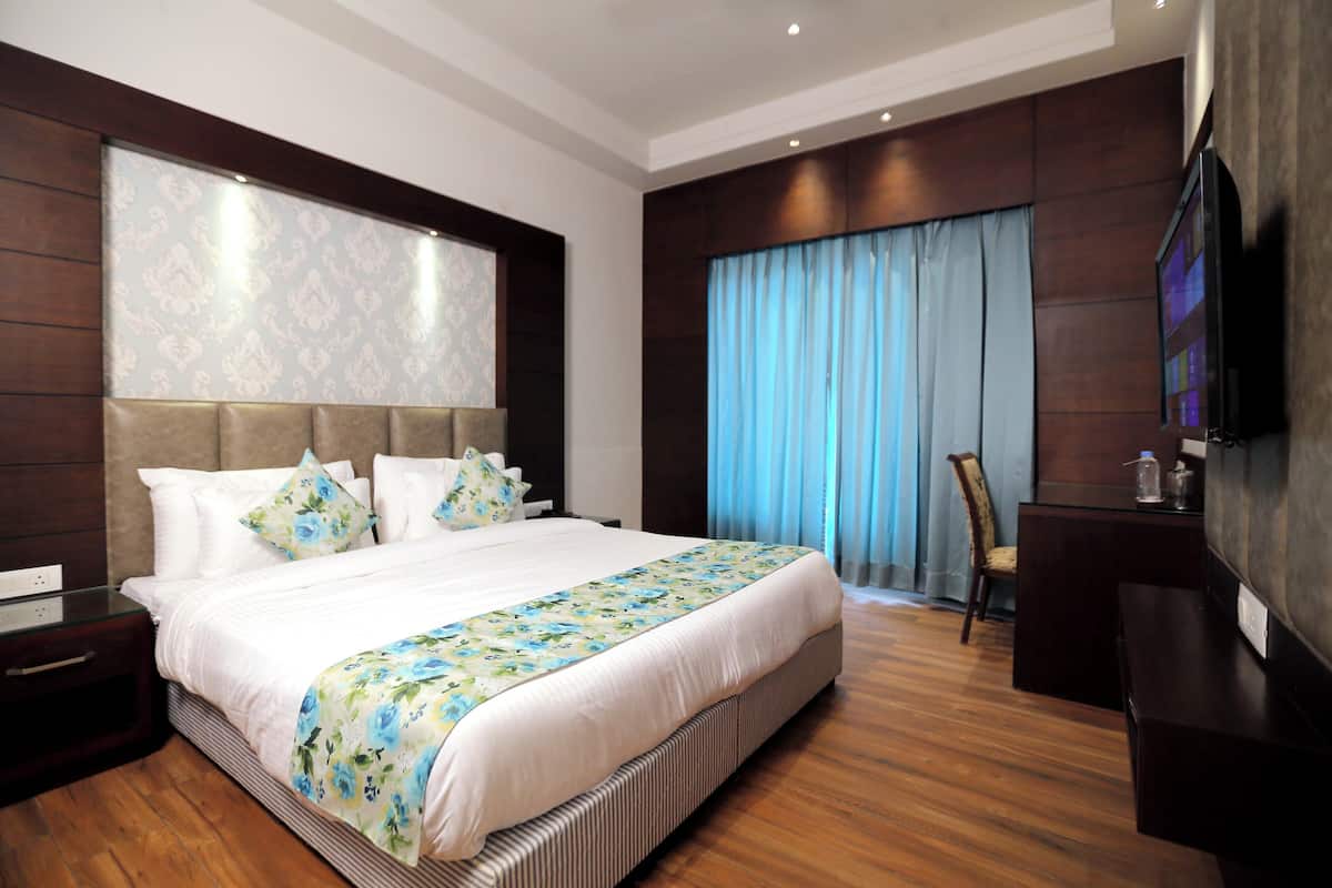 Una habitación de hotel moderna con una cama grande, un televisor de pantalla plana y piso de madera.